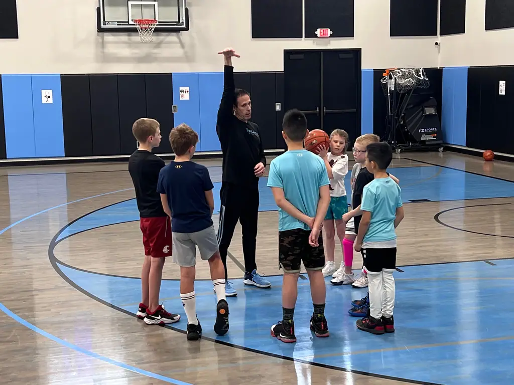 A coach demonstrating shooting form for young players