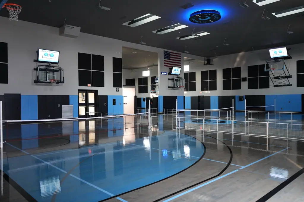 The gym floor with pickleball nets set up and an American flag on the far wall
