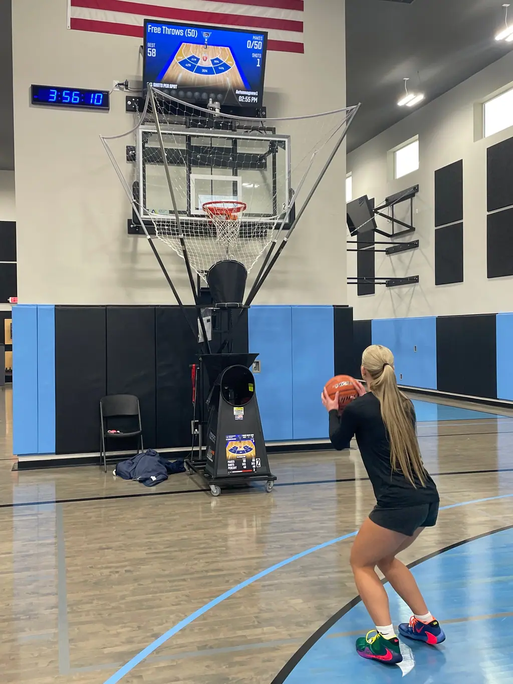 An athlete shooting free throws into The Gun's net, with a shot-tracking screen above the hoop