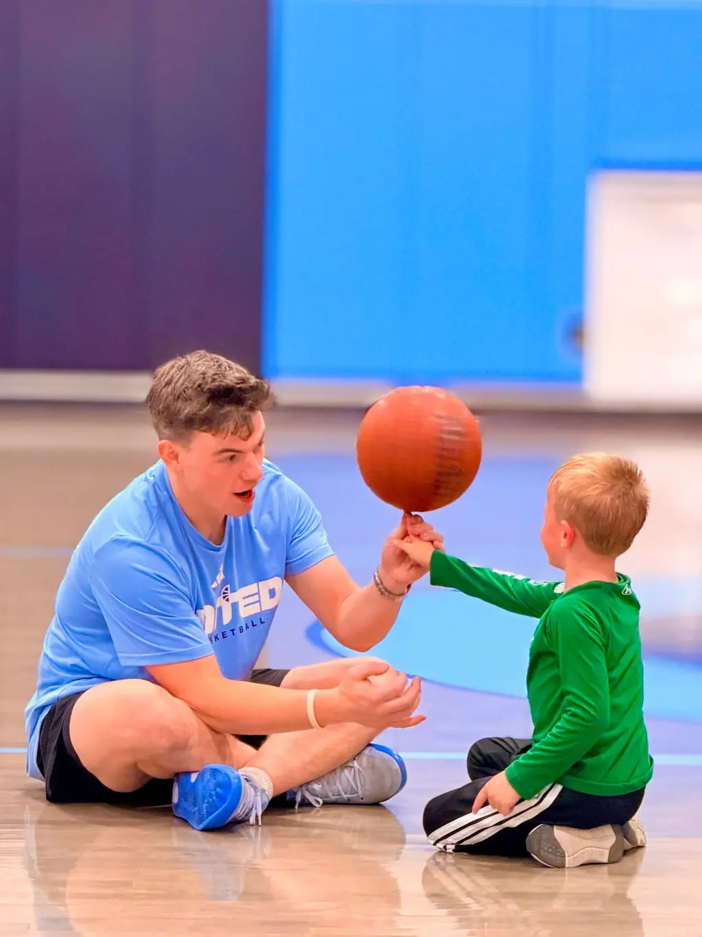 Adult seated with a small child and basketball