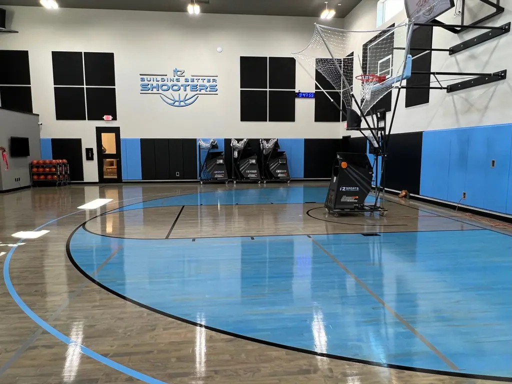 The shooting court with shooting machines lined up beneath a Building Better Shooters wall sign